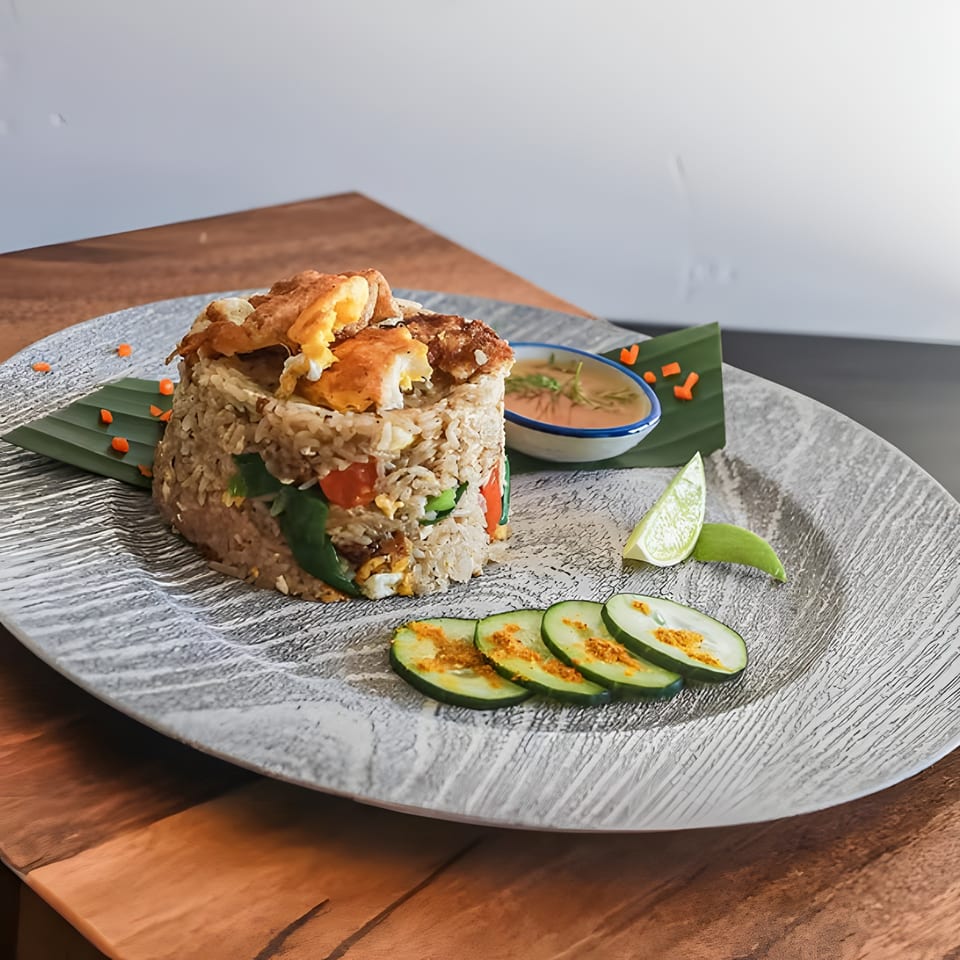 BAHT's Thai fried rice with crispy egg, cucumber, lime, and dipping sauce on a textured plate.